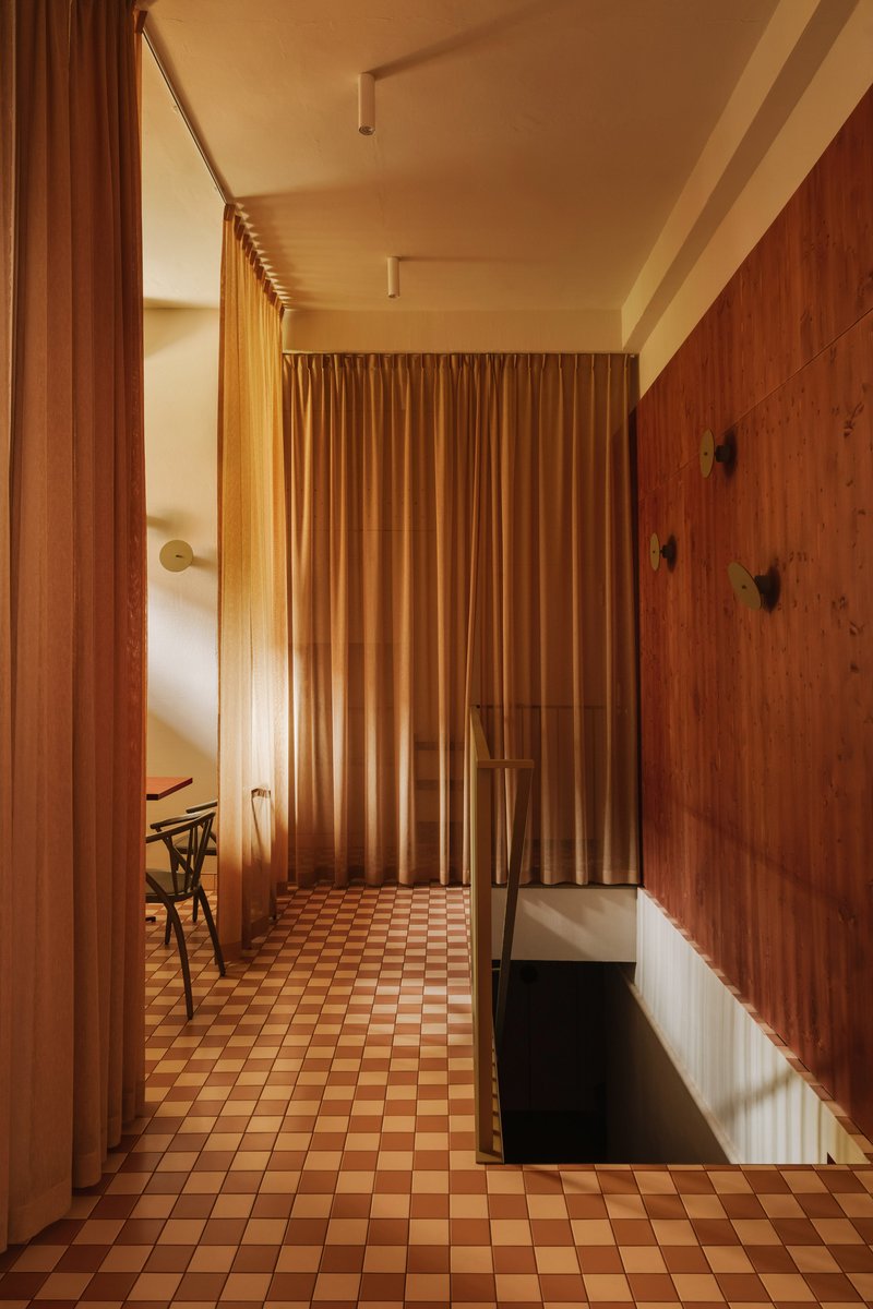 Corridor with floor-to-ceiling curtain divider and checkered tile floor in warm afternoon light