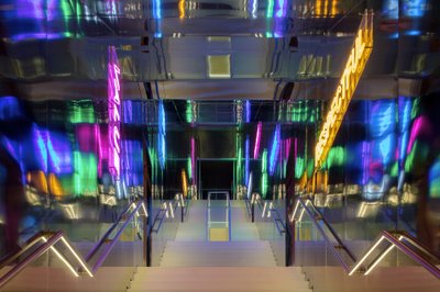 This architectural image showcases a modern staircase illuminated by vibrant neon lights and reflect