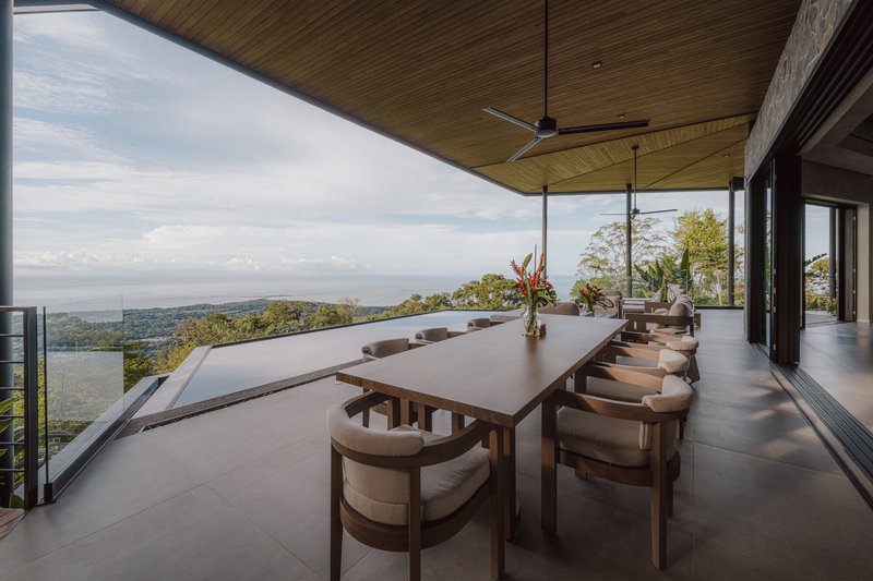 Dining terrace with timber ceiling and table overlooking valley and distant coastline