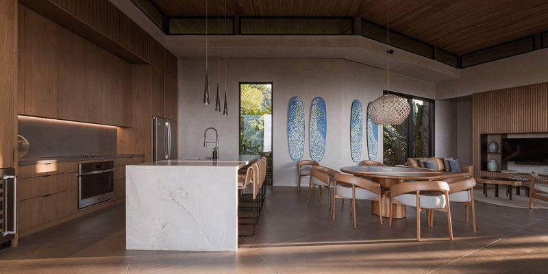 Kitchen island with white veined marble under a timber-clad ceiling and concrete beam