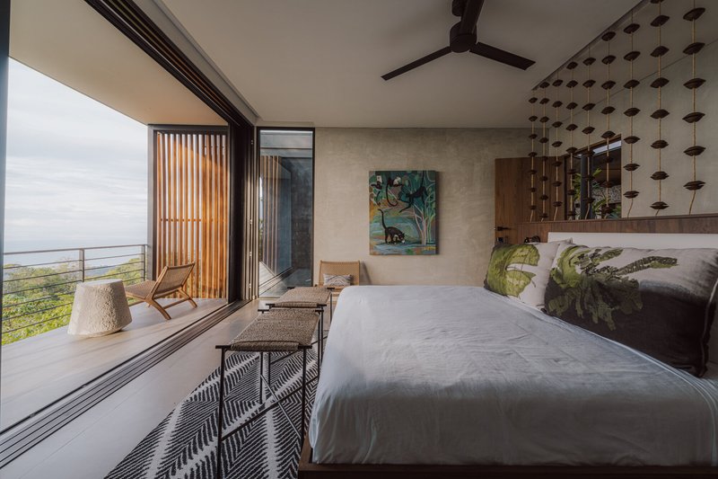 Bedroom with corner glazing, timber louver screen, and perforated panel headboard wall at dusk