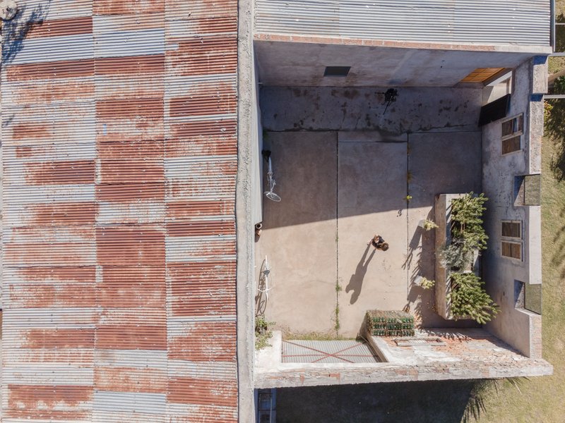 Top-down view of the concrete courtyard between weathered corrugated metal walls and planted beds