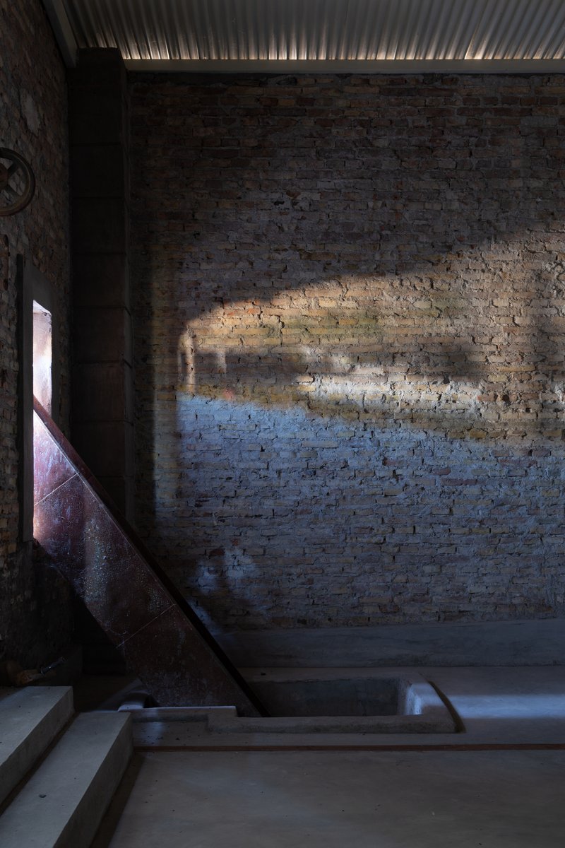 Interior staircase with steel handrail and exposed brick wall illuminated by natural light