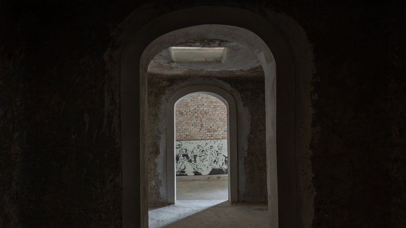 Sequence of arched brick doorways leading through dimly lit vaulted interior spaces