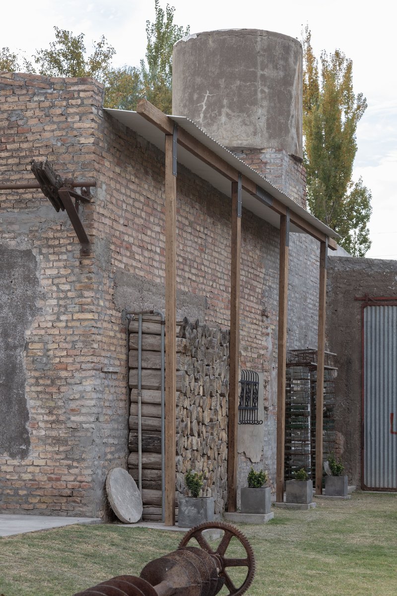 Freestanding timber frame with slanted rafters anchored to the weathered brick wall and water tower beyond