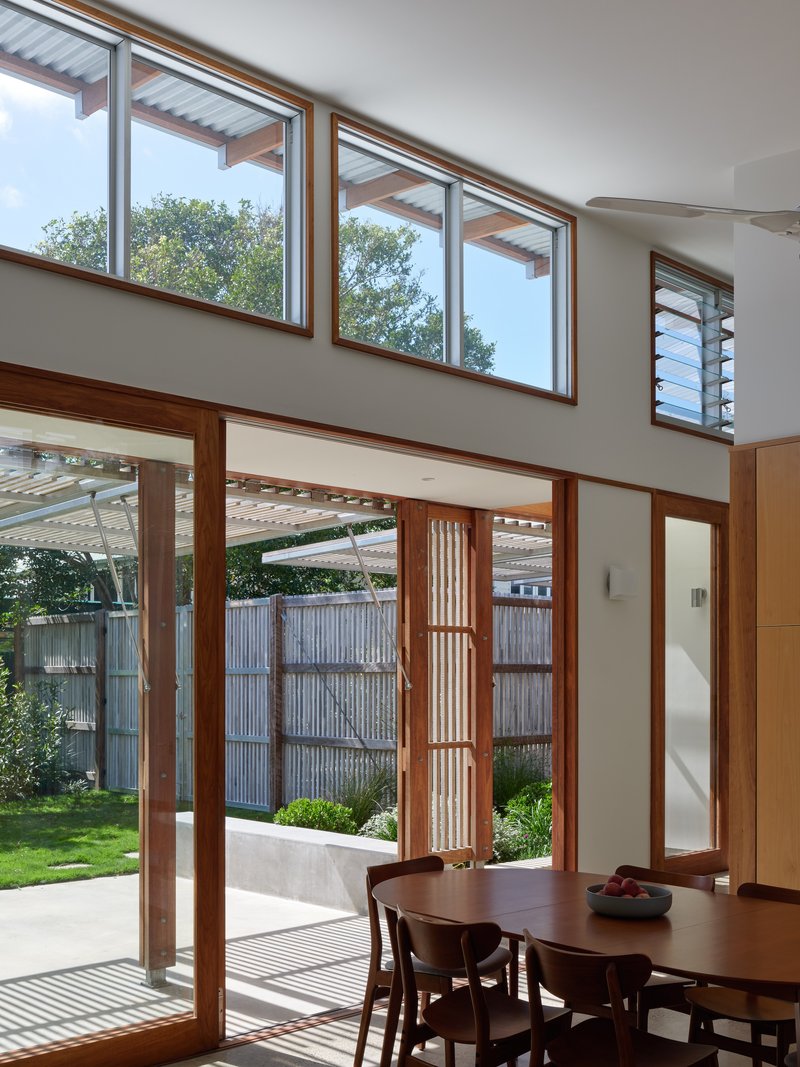 Dining area with timber-framed glazing looking out to the screened courtyard and clerestory windows above