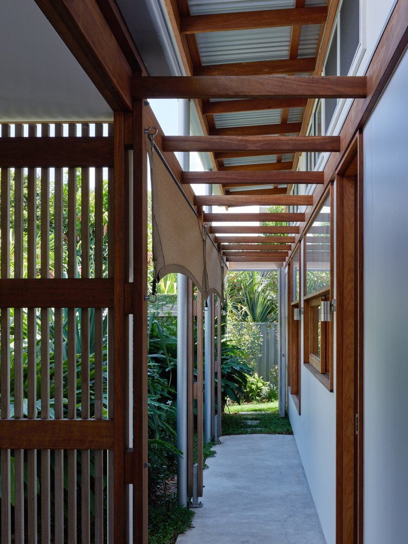 Covered walkway with timber pergola and slatted screening opening onto a garden path