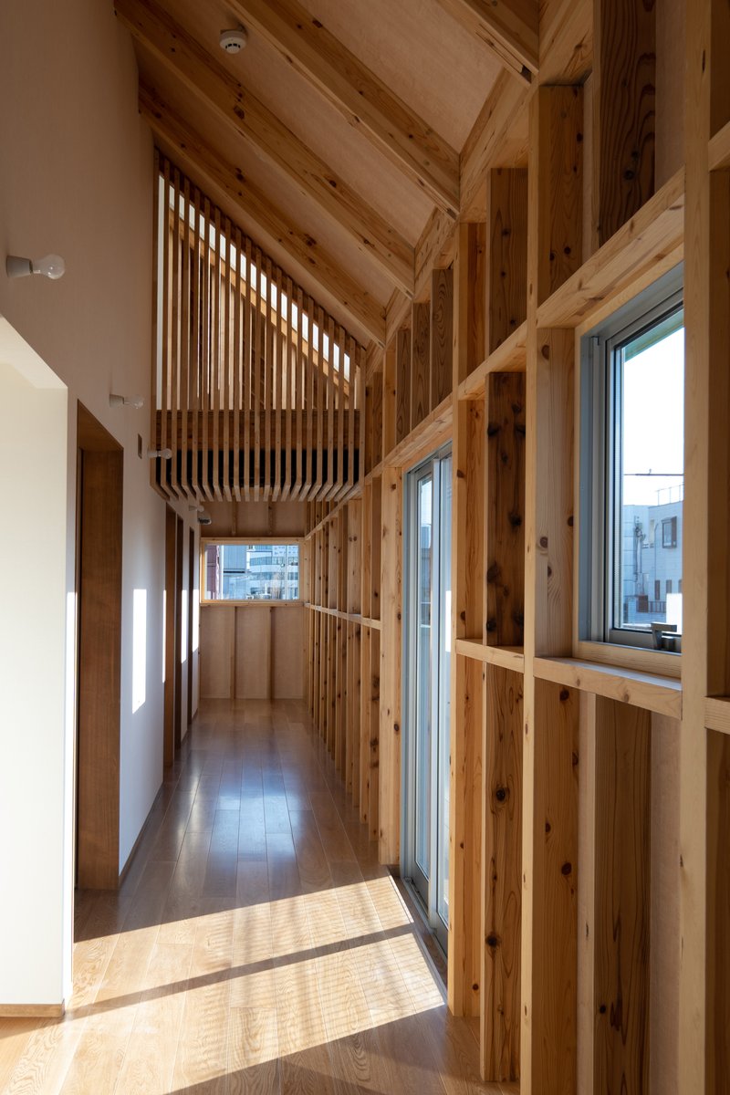 Hallway with exposed timber framing and suspended louvered light fixture in afternoon sun