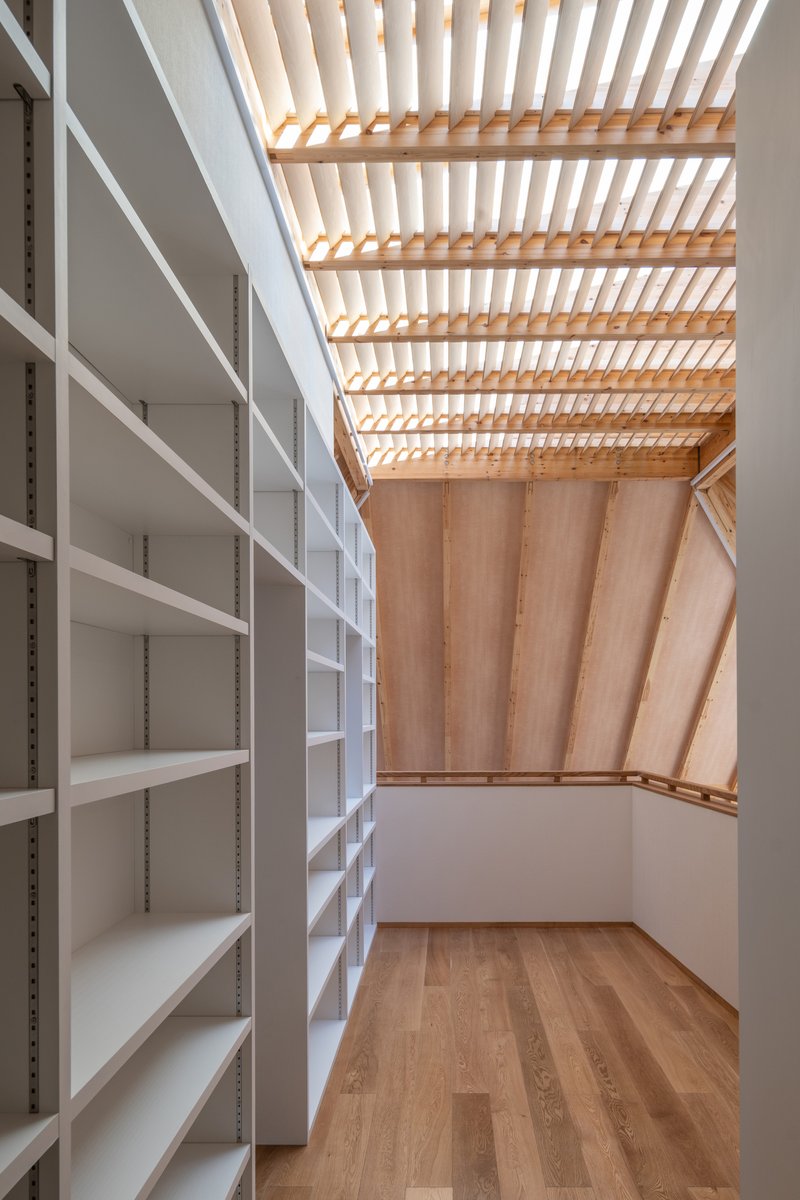 Storage room with white adjustable shelving beneath a slatted timber skylight