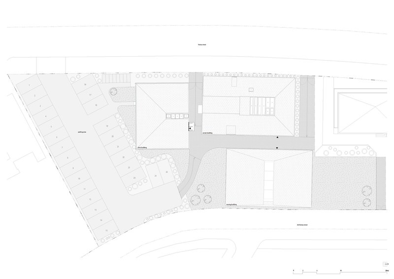 Site plan drawing showing rectangular volumes arranged around a courtyard with adjacent parking lot