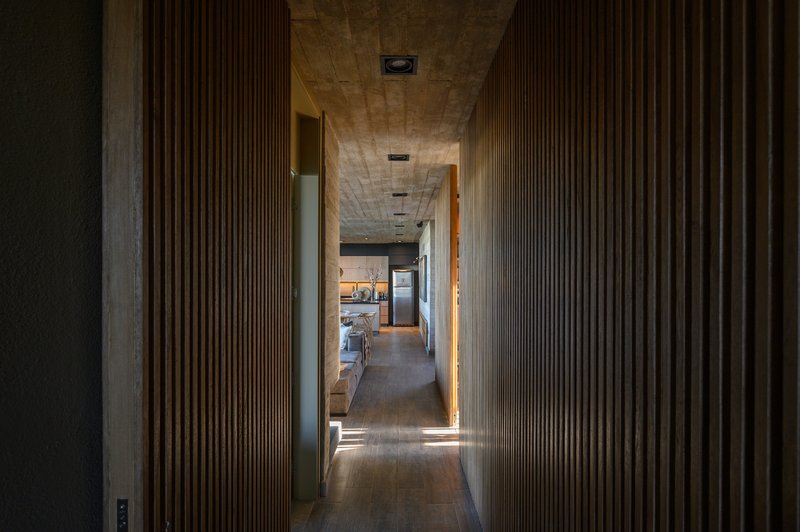 Interior corridor with vertical wood slat walls and timber ceiling leading toward a kitchen beyond