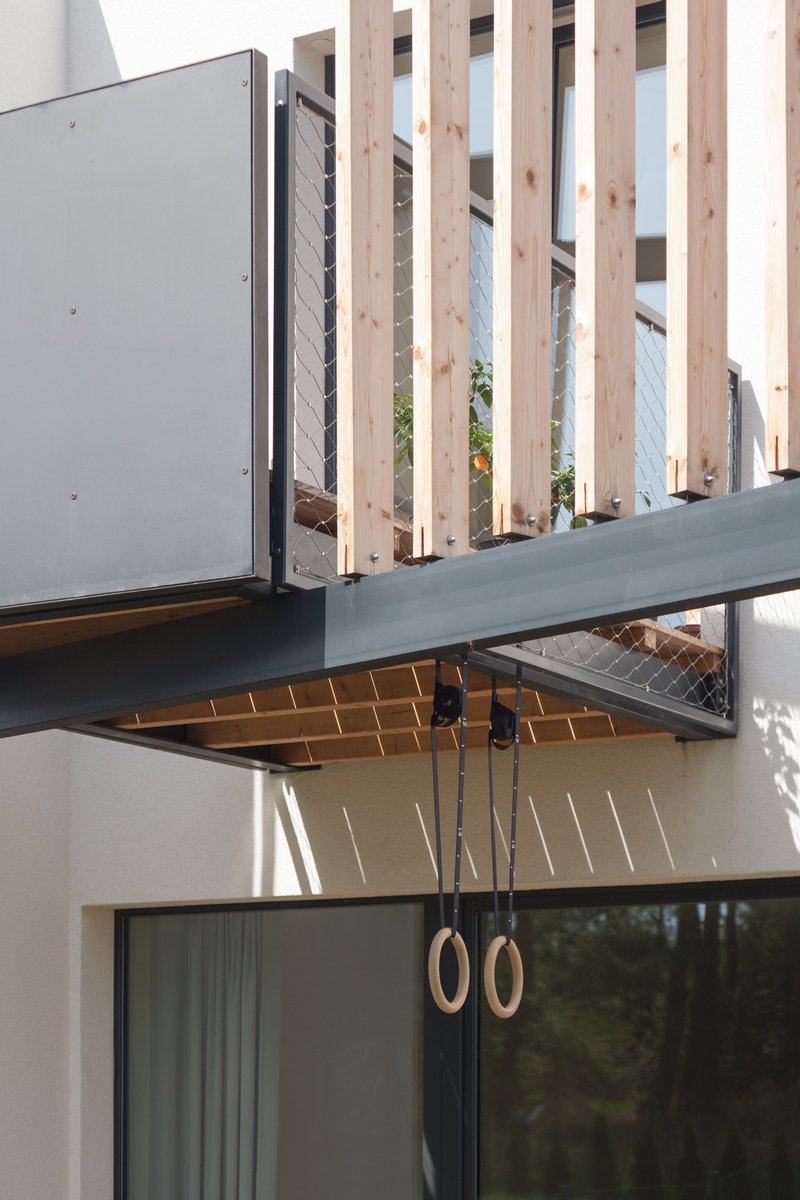 Steel frame and vertical wooden slats form a secondary skin, enhancing shading, depth, and spatial buffering.