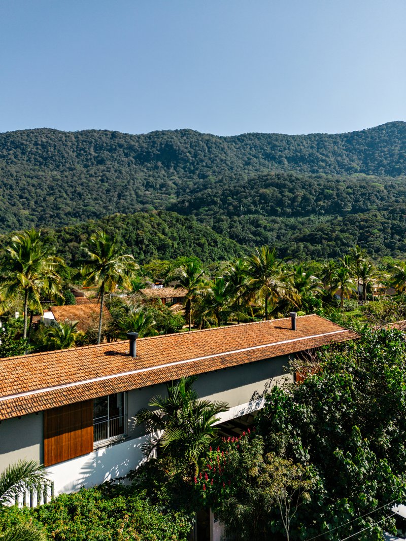 Elevated view of the terracotta tiled roof set among palm trees and forested mountains
