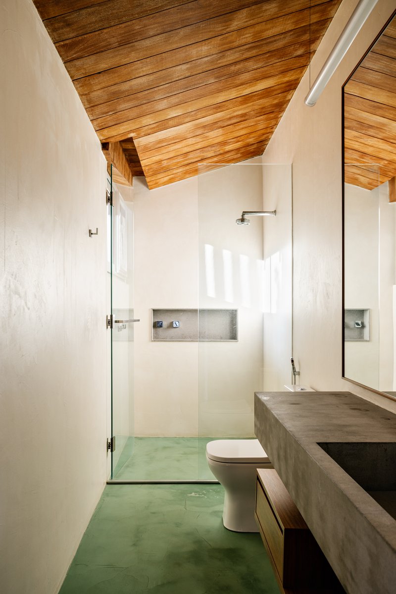 Bathroom with green polished concrete floor, exposed timber ceiling, and recessed shower niche