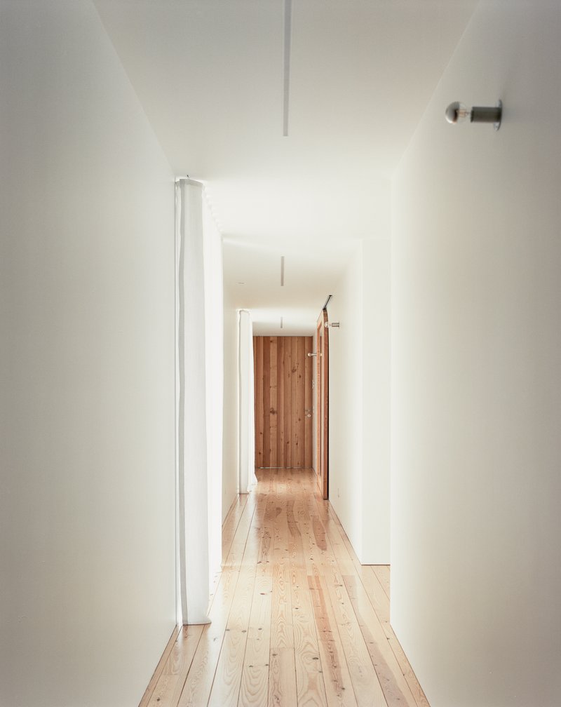White-walled corridor with pale timber flooring and a recessed ceiling channel of light