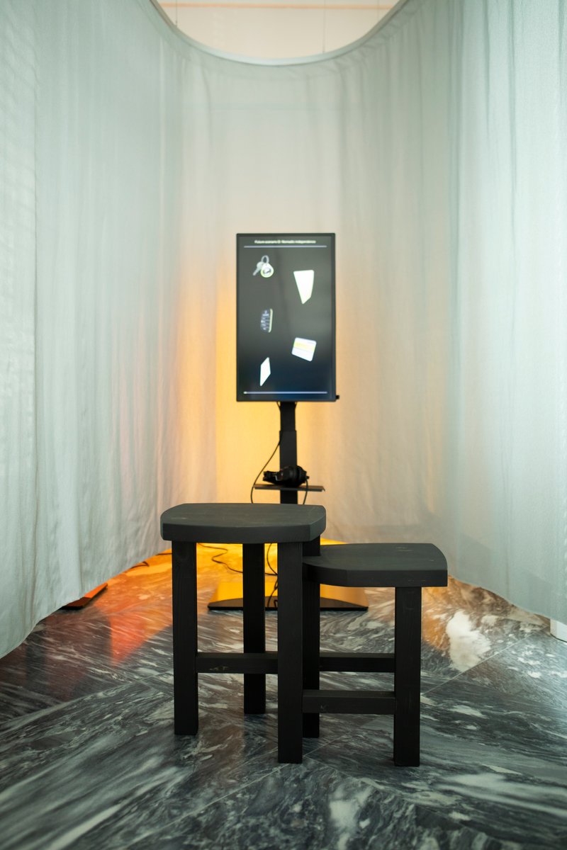 Black display panel and stools in curtained alcove with warm backlighting on marble floor
