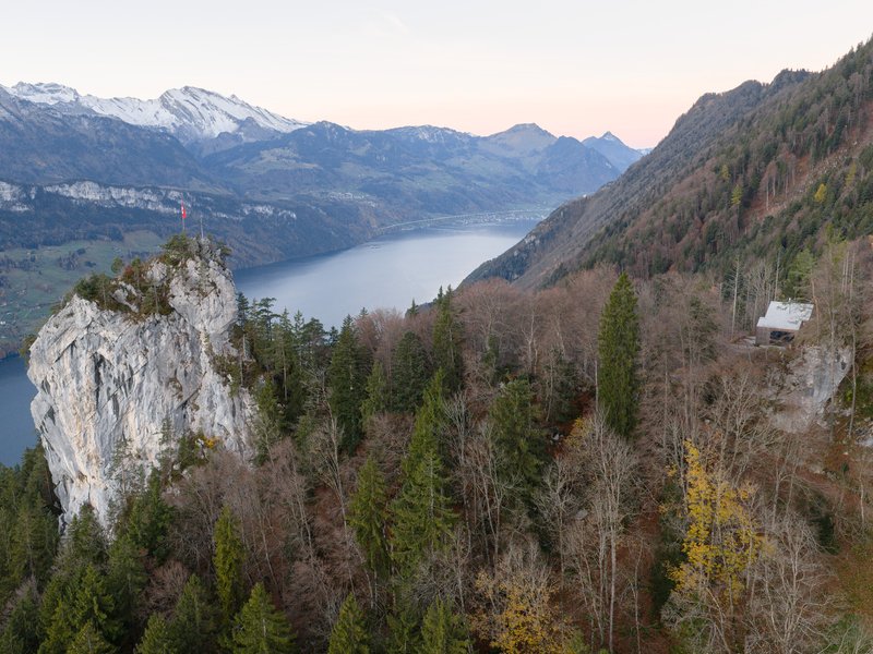 Distant view of the roofline against mountain peaks and a lake valley in late afternoon light