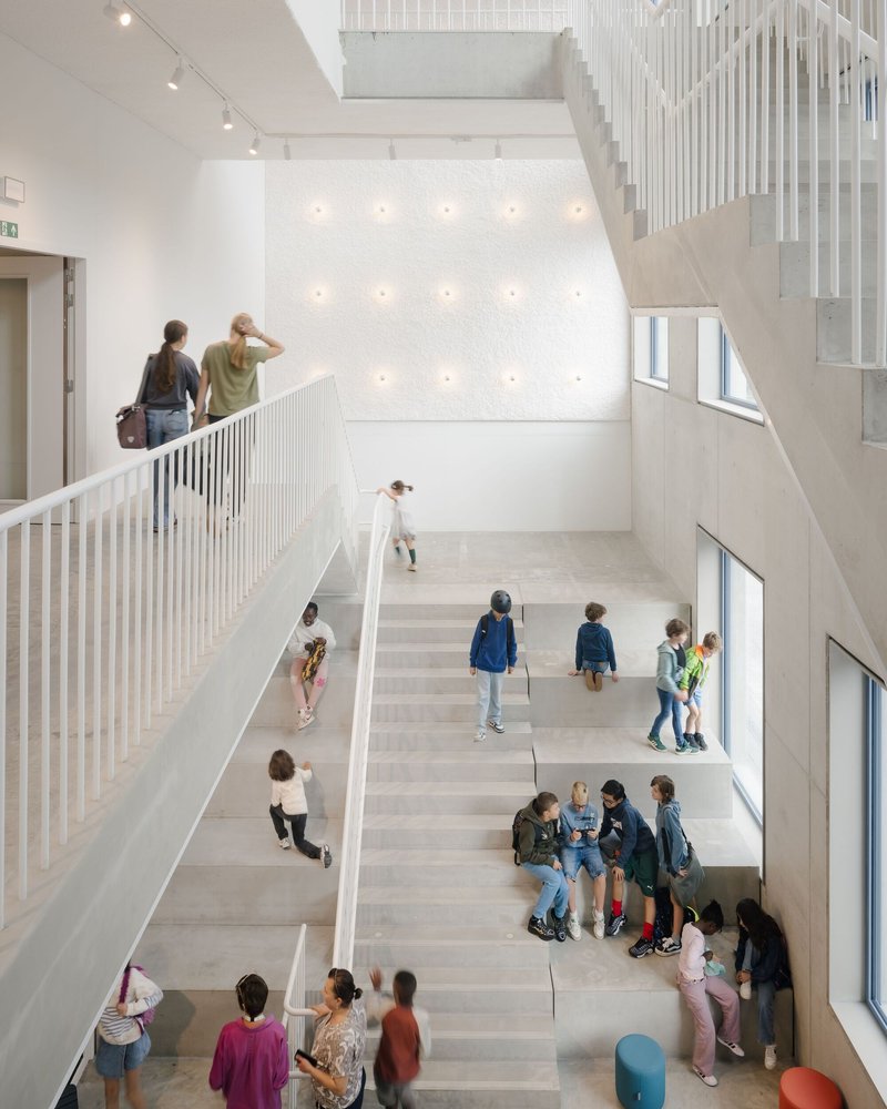 Atrium staircase with white balustrades and terrazzo treads filled with children gathering and playing