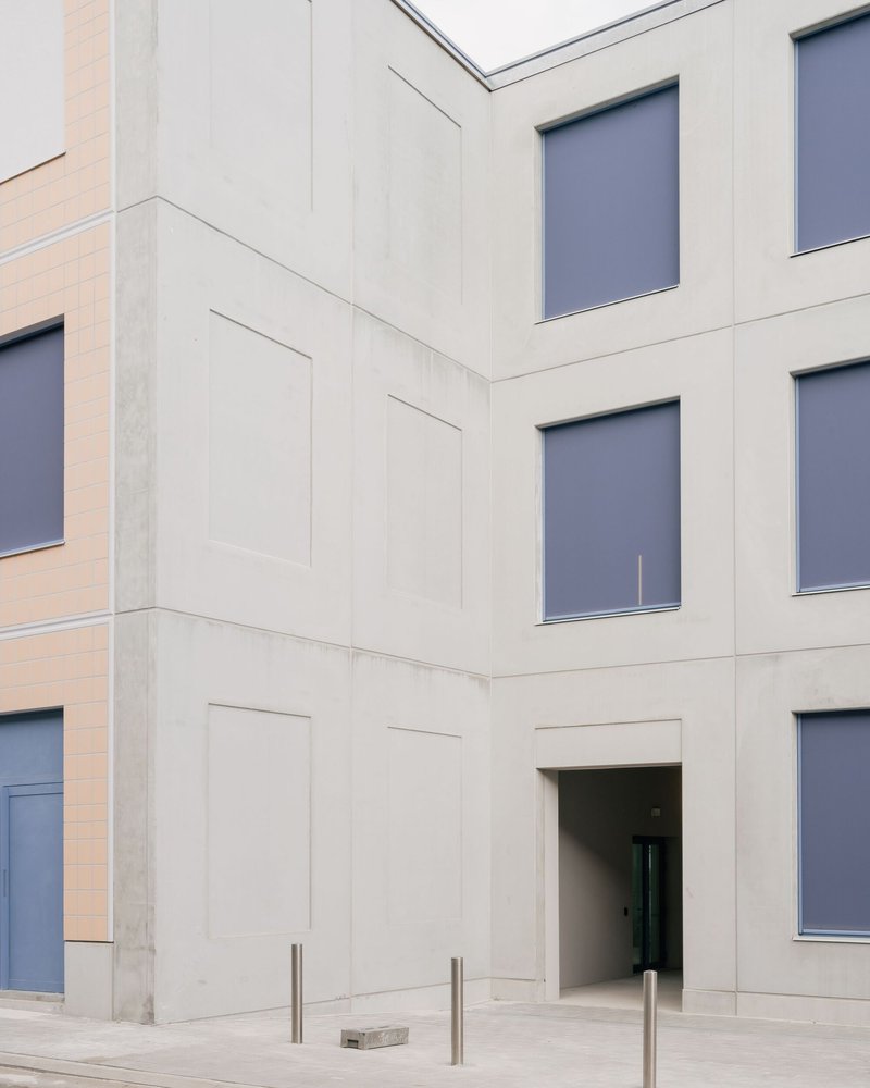 Corner detail of precast concrete panels with recessed doorway and steel bollards