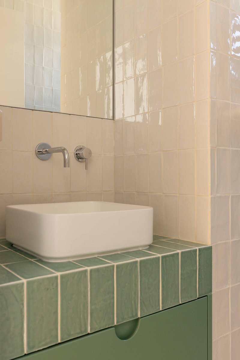 White rectangular basin on a green tiled countertop with wall-mounted chrome faucet
