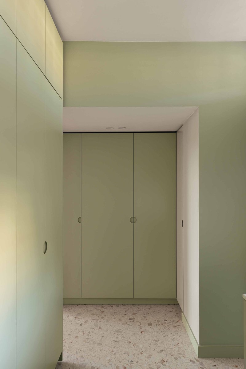 Hallway with sage green built-in wardrobes framing a doorway and terrazzo floor