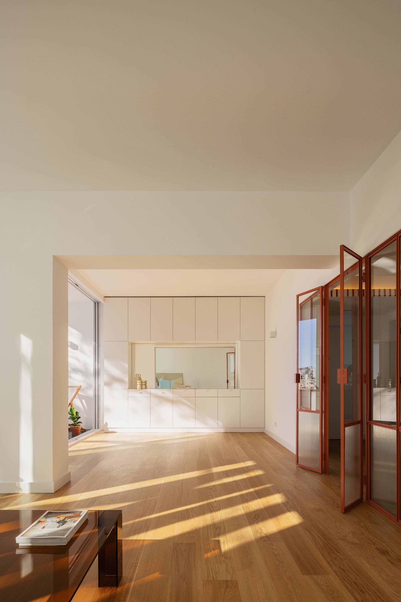 Open living space with timber folding doors and diagonal shadows cast across the oak floor