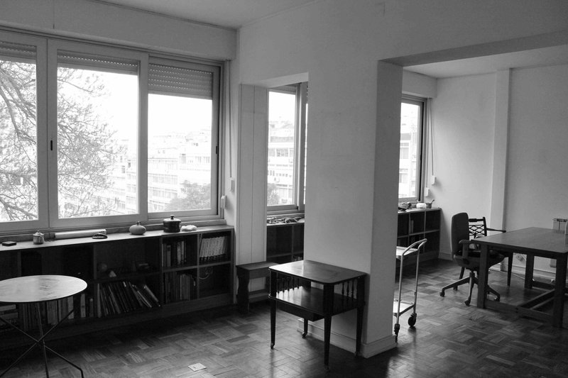 Black and white photograph of an open plan interior with parquet flooring and low bookshelves