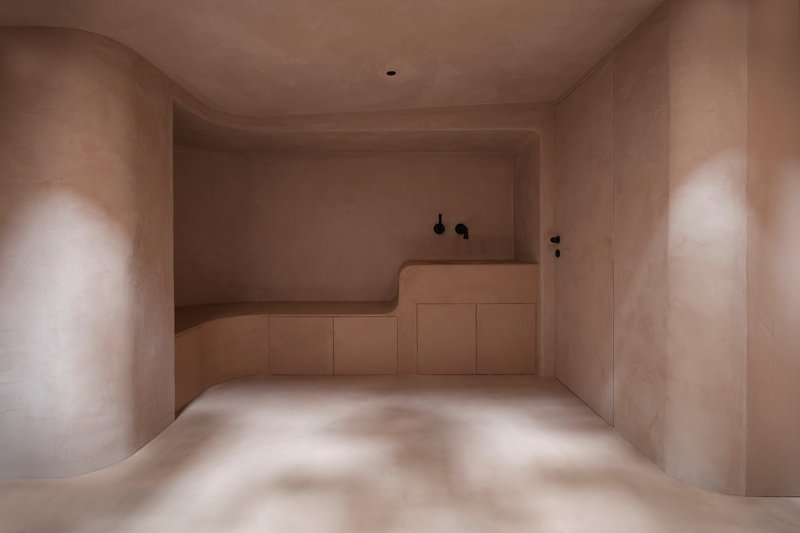 Bathroom with integrated bathtub and vanity in pale plastered walls with soft daylight from above