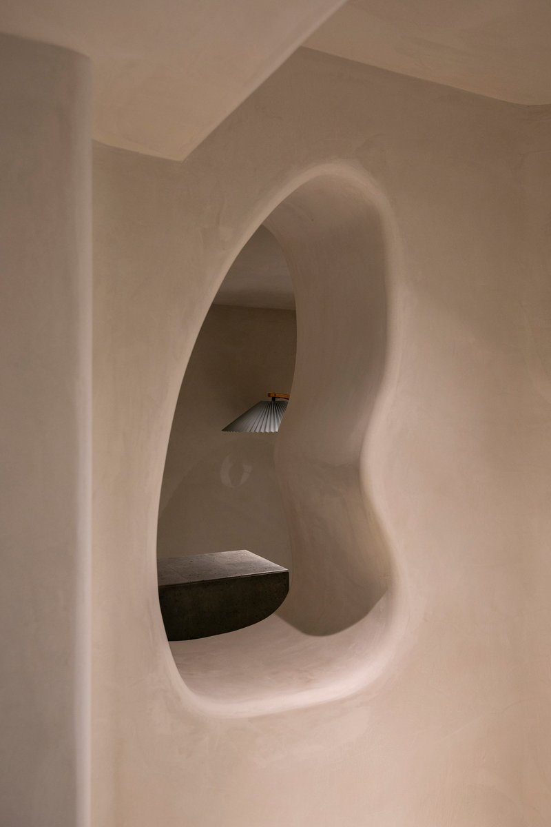 Arched alcove carved into plastered wall with integrated bench and shell-form sconce