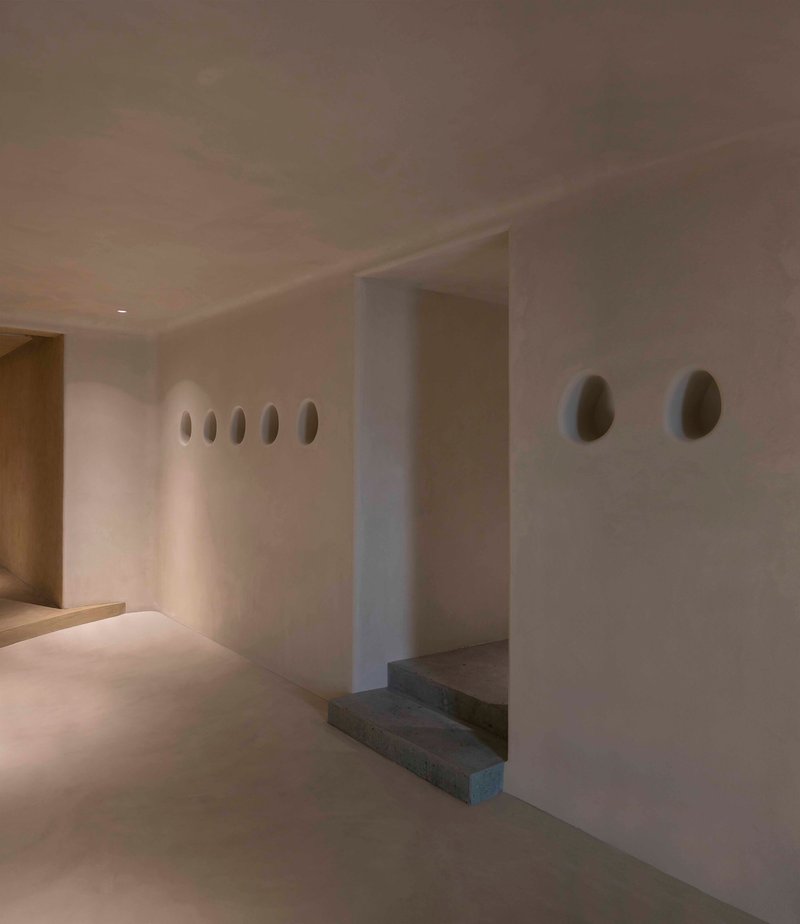 White plastered wall with oval niches and stone steps set into an alcove niche