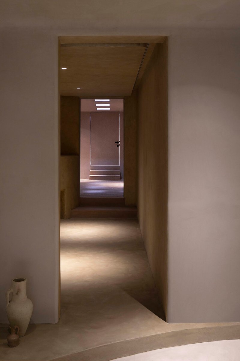 Sequence of thresholds leading to a backlit door at the end of a long corridor