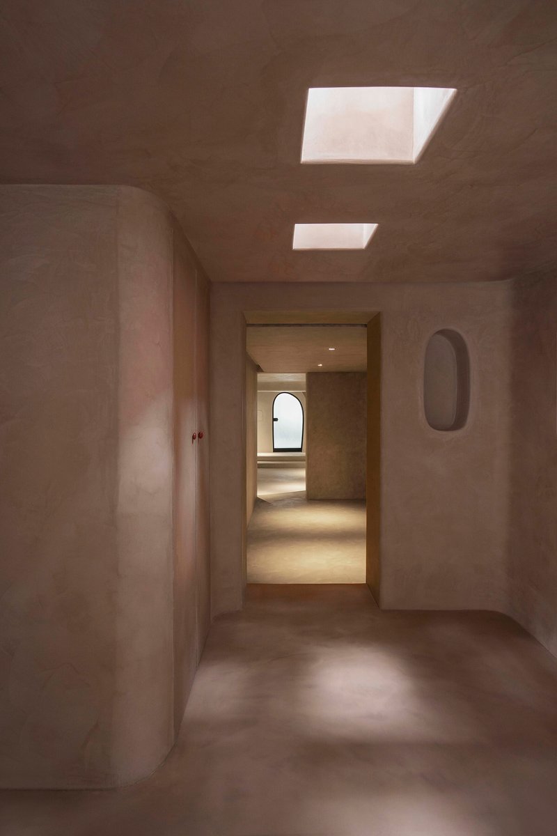Plastered room with rectangular skylights and doorway framing a view through multiple chambers