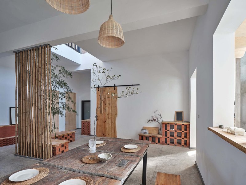 Interior dining area with woven pendant lamps, timber screen, and skylight casting daylight onto polished concrete floor