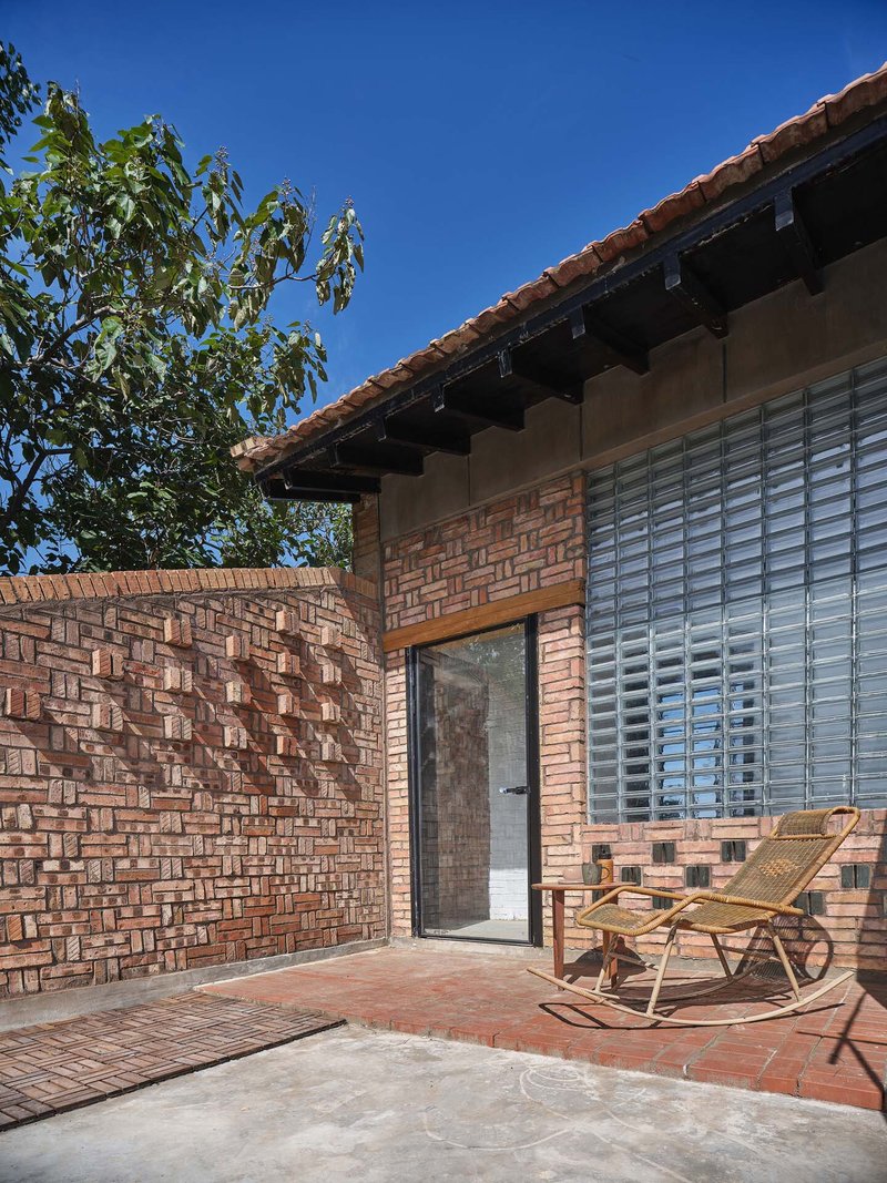Terrace corner with woven brick privacy wall and glass block window beneath clay tile eaves