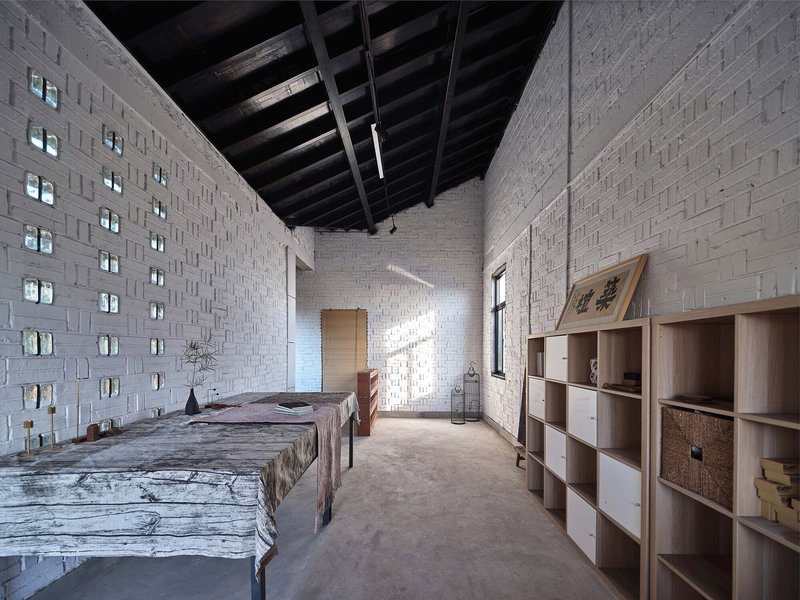 Bedroom with perforated white brick walls and exposed timber ceiling beams in afternoon light