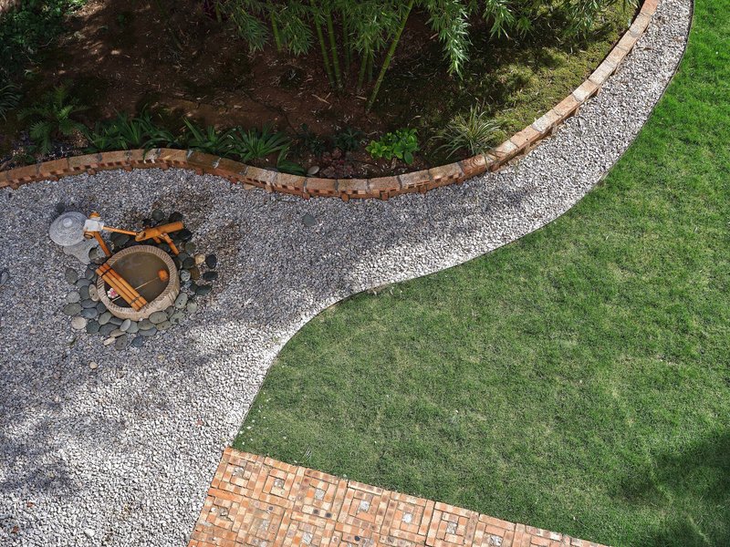 Aerial view of curved gravel pathways separating lawn and planted beds with bamboo and a central fire pit