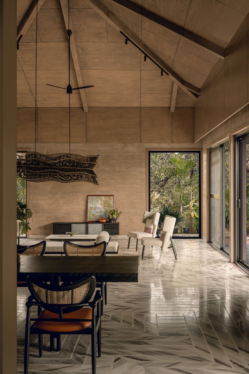 Living area with herringbone stone flooring and pitched wood-paneled ceiling lit by afternoon sun