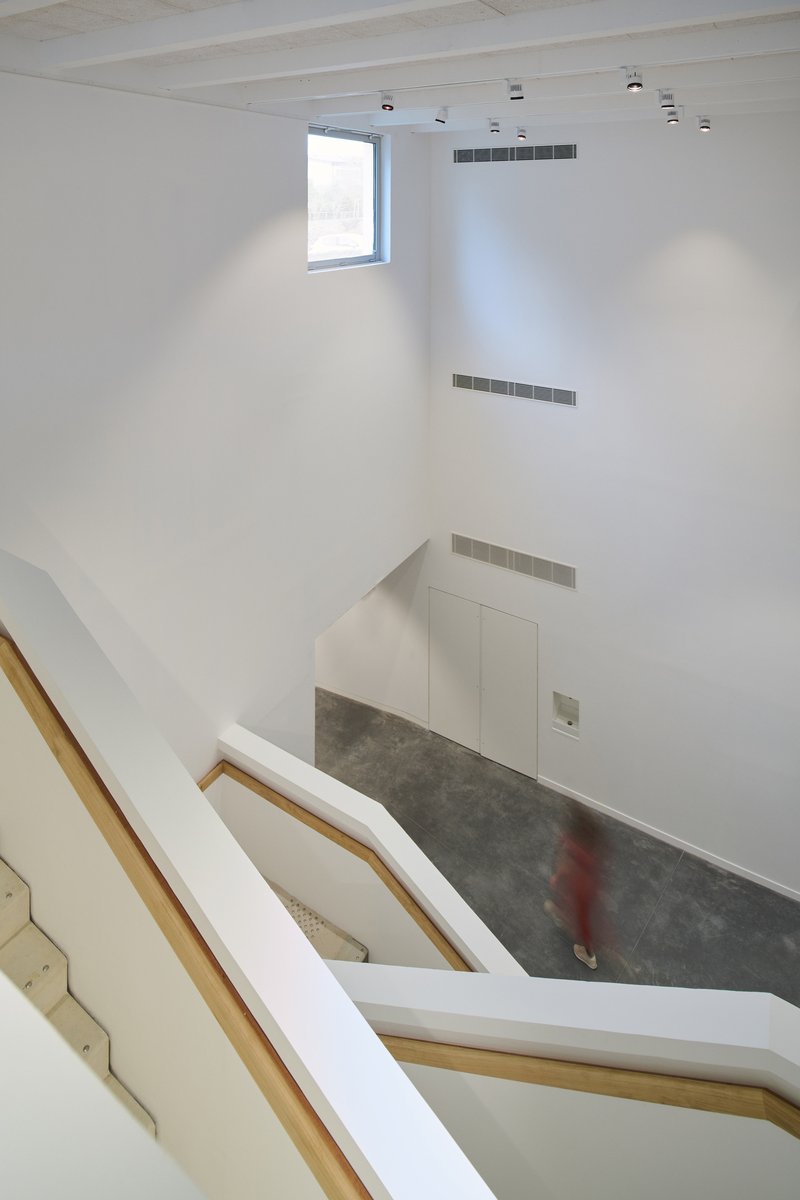 View down through stairwell showing angled handrails and a figure in red on the floor below