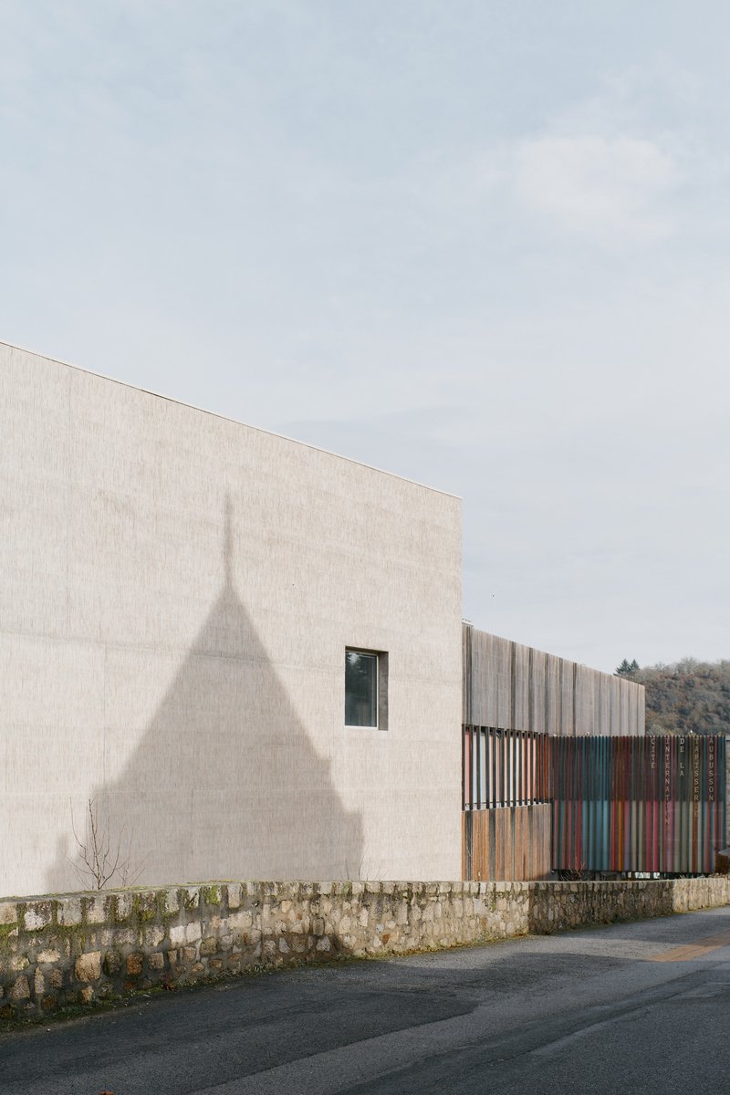 Shadow of a tower cast on pale concrete wall above a low stone wall