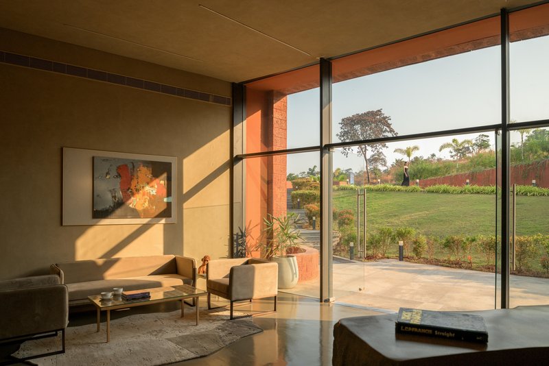 Living area with floor-to-ceiling glass doors framing a planted lawn in warm afternoon sun