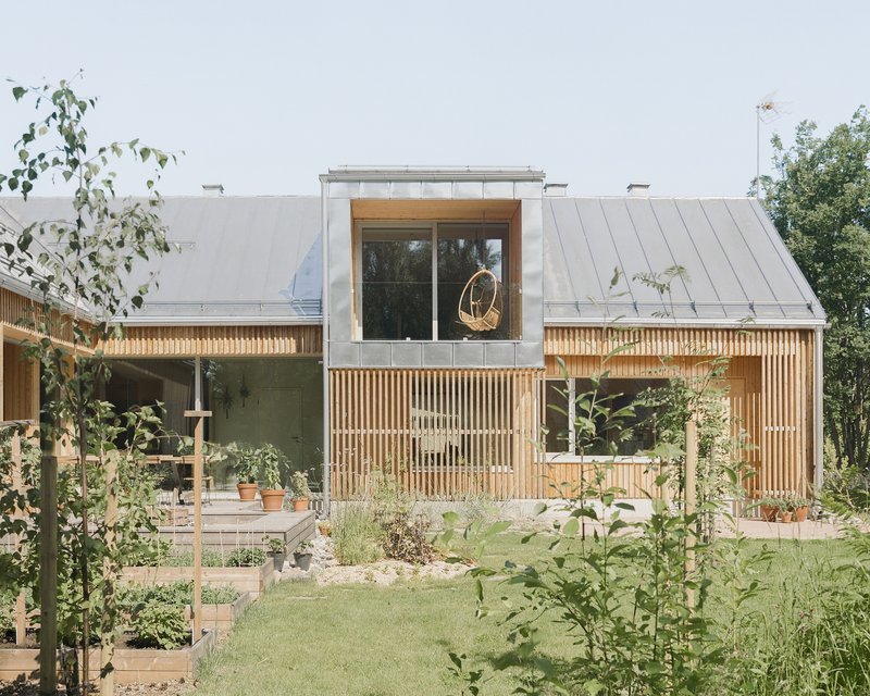 Garden view of the timber-clad volume with vertical slat screen and metal roof beyond raised vegetable beds