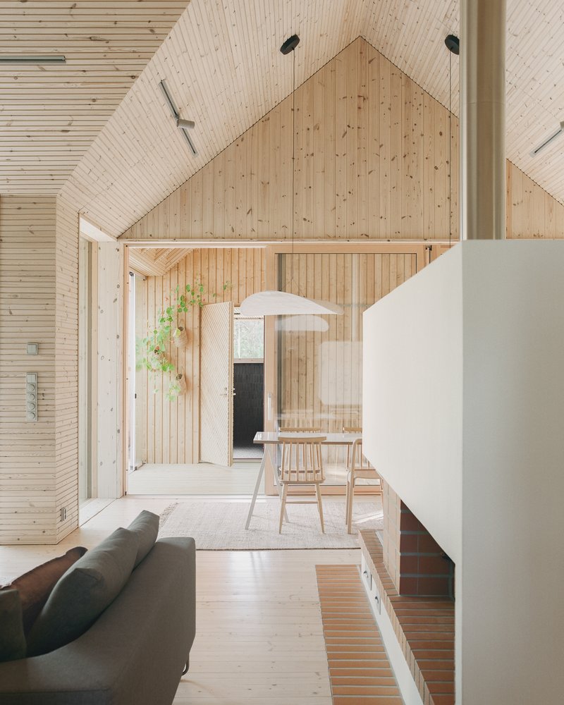 Interior view of timber-lined living space with exposed gable ceiling and white fireplace volume