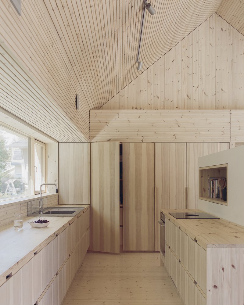 Kitchen with timber cabinetry and paneled ceiling beneath intersecting gable roof volumes