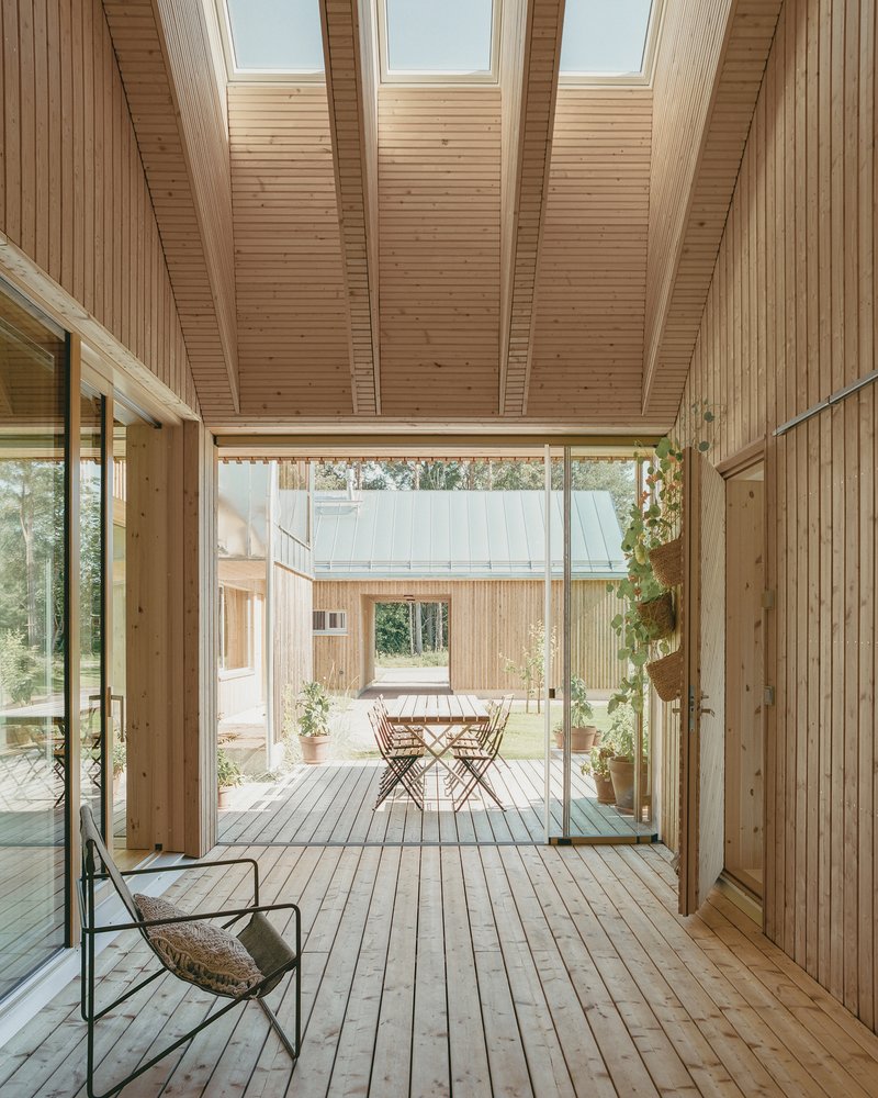 Interior courtyard with timber decking, skylights overhead, and folding chairs visible through glazed opening
