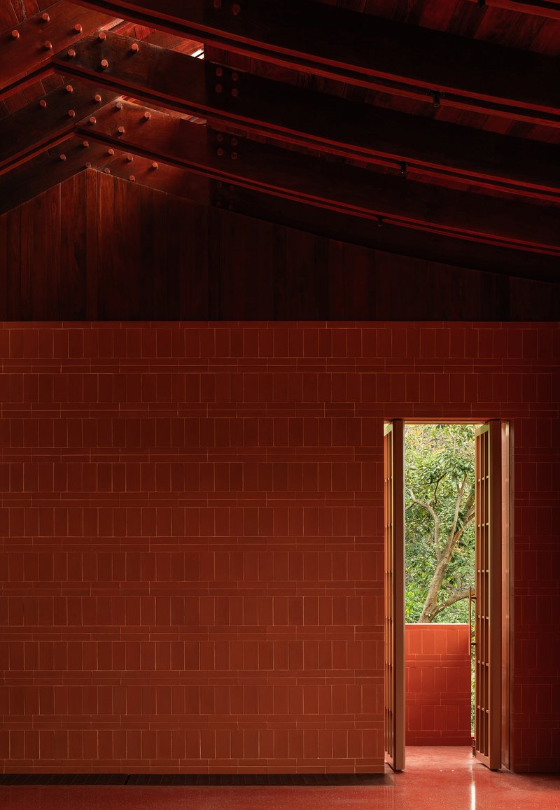 Interior volume with red tile walls and exposed timber roof structure above an open doorway
