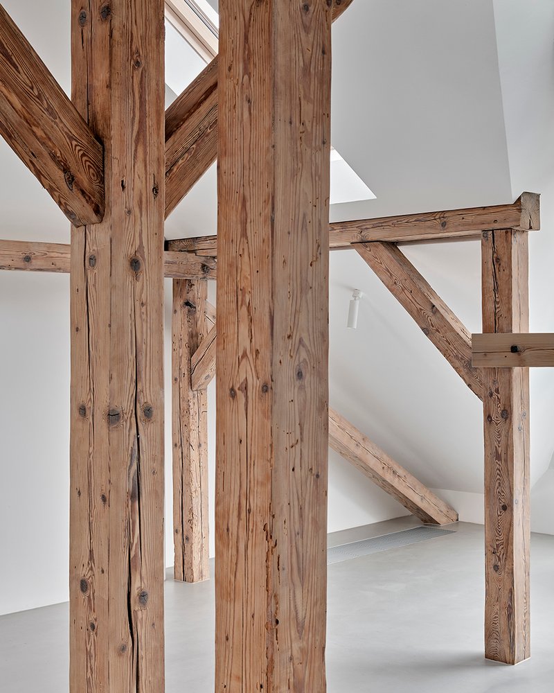 Close-up of reclaimed timber post and beam joinery with white plaster walls in background