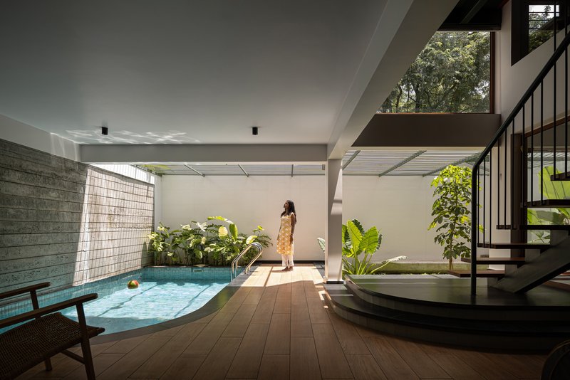 Interior courtyard with lap pool, timber deck, and perforated metal screen filtering sunlight above
