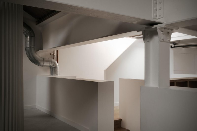 Open interior with exposed ductwork, white partitions, and painted steel columns under natural light