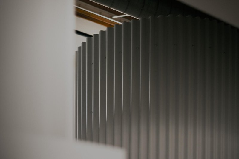 Close-up of vertical metal fins extending from ceiling with timber beams visible above