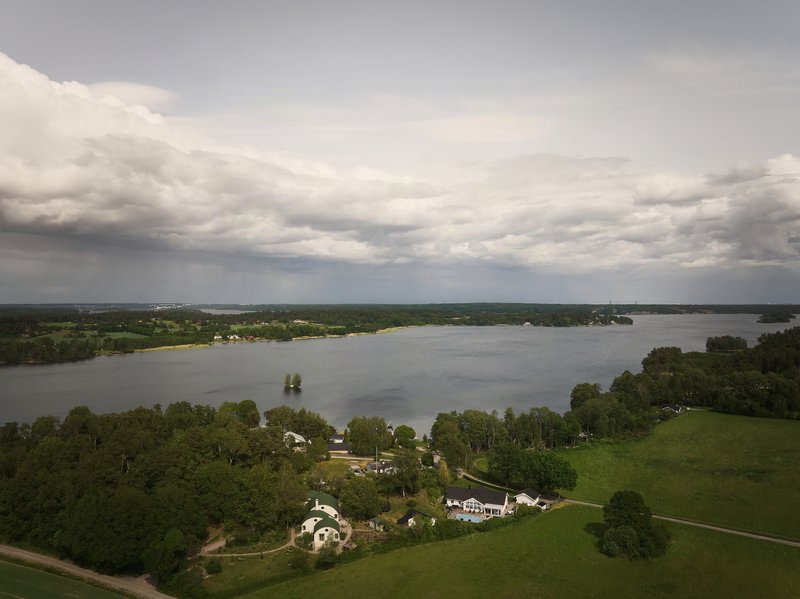 Aerial view of the cluster of barrel-roofed structures nestled among trees beside a lake under storm clouds